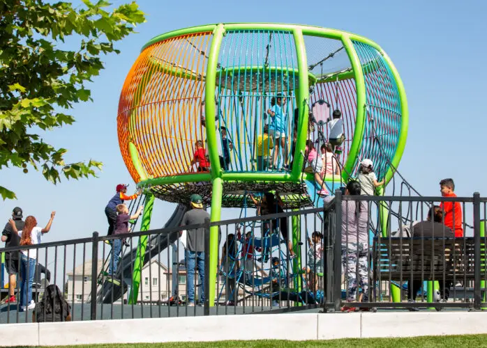 A vibrant playground filled with children joyfully playing on swings, slides, and climbing structures.